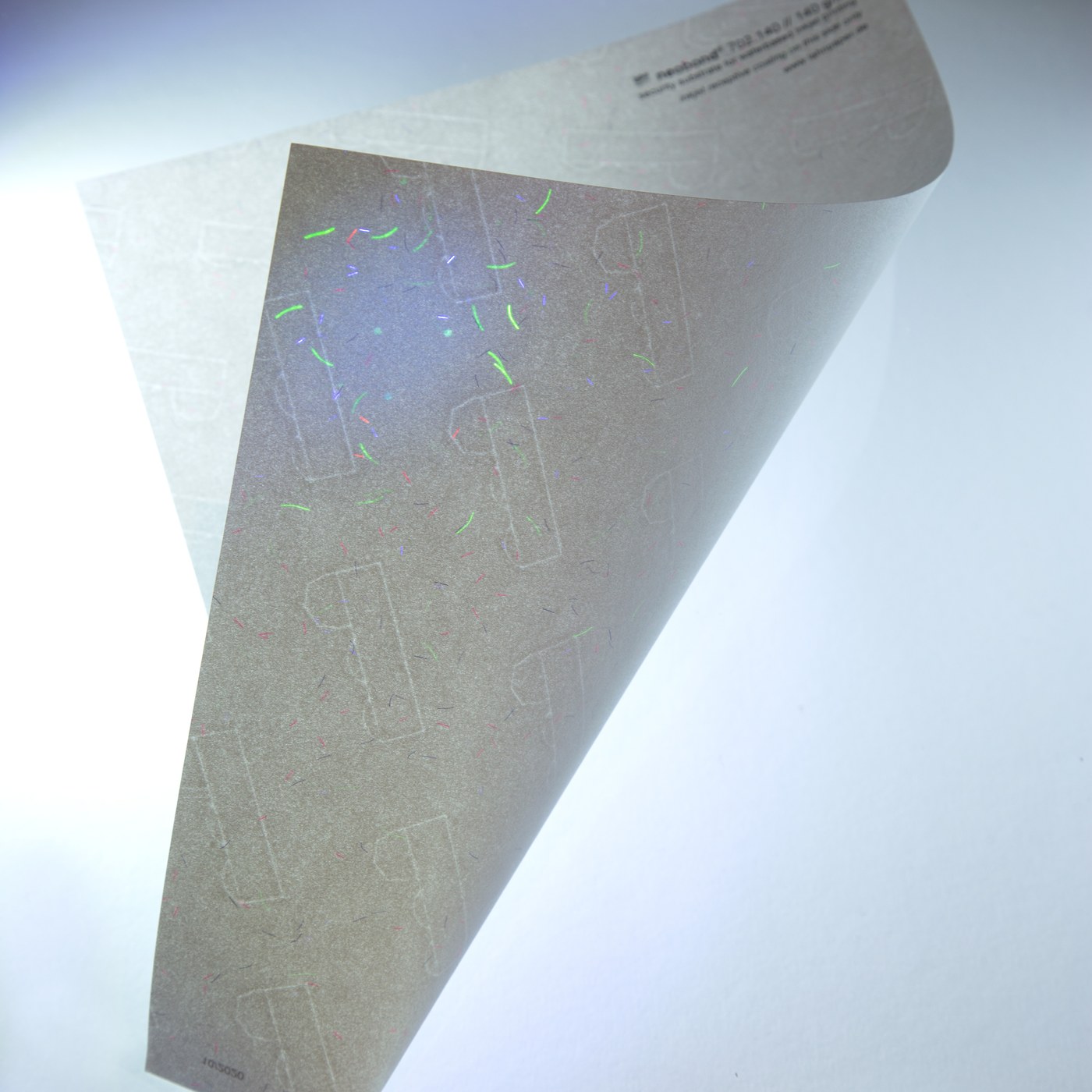 Papel de seguridad Neobond mostrando fibras y marca de agua bajo luz rasante